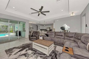 A modern living room with a sectional sofa, a coffee table, and a ceiling fan.
