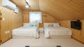 A room with two beds, a television, and an air conditioning unit.