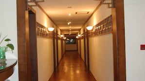 Un long couloir étroit, doté d’un plancher et de murs en bois, bordé de luminaires régulièrement espacés et de tableaux encadrés.