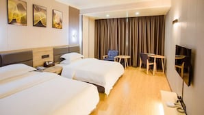 Une chambre d’hôtel avec deux lits, un bureau, une chaise, une télévision et un rideau.