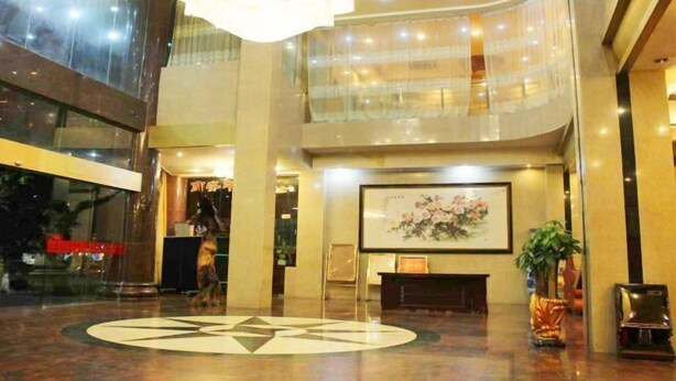 Un hall d’entrée spacieux, agrémenté d’un grand lustre, d’un comptoir de réception et d’une œuvre d’art encadrée au mur.