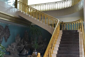 A curved staircase with golden railings inside a building. - Bailegong Hotel Xinfeng (Xinfeng)
