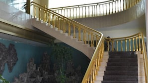 Un escalier en colimaçon, doté de rampes dorées et de marches sombres, menant à un niveau supérieur.