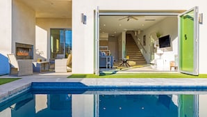Une maison moderne dotée d’une piscine, d’un espace salon extérieur et d’un escalier menant à un étage supérieur.