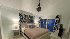A bedroom with a bed, nightstands, a lamp, a television, and a view of the outside. - 3 BR sleeps 10 WATER FRONT w BOAT SLIP + FABULOUS POOL  (Treasure Cay)