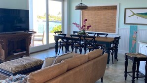 A living room with a sofa, TV, dining table, chairs, and a view of the outdoors. - 3 BR sleeps 10 WATER FRONT w BOAT SLIP + FABULOUS POOL  (Treasure Cay)