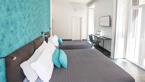 Quarto de hotel com duas camas, uma mesa e uma televisão.