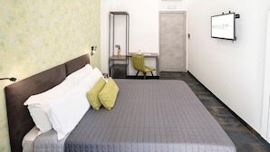 Quarto com cama, escrivaninha, cadeira e porta.