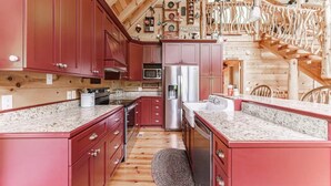 A kitchen with red cabinets, granite countertops, a stainless steel refrigerator, and a wooden ceiling with exposed beams. - Powdermill Hill Cabin 3 Bedroom Cabin by RedAwning (Gatlinburg)