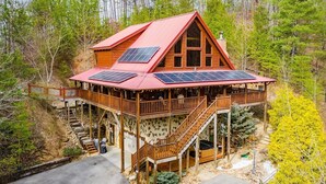 A wooden cabin with a red roof, solar panels, and a balcony. - Powdermill Hill Cabin 3 Bedroom Cabin by RedAwning (Gatlinburg)