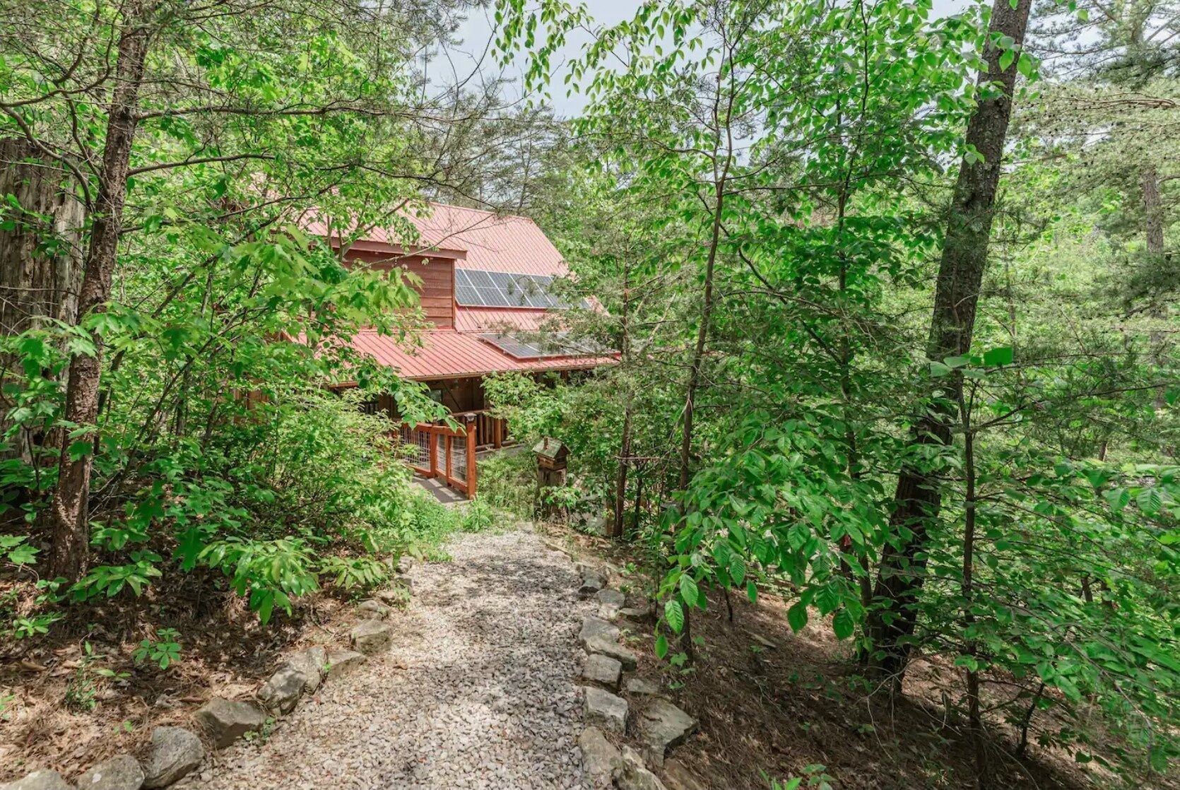 Una casa di legno rustica con tetto rosso, immersa in una fitta foresta.