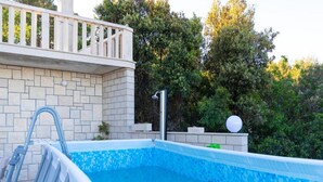 Piscina com borda azulejada, escada de metal e guarda-corpo branco.