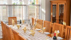 Un coin repas avec une nappe à carreaux, des chaises en bois et un buffet aux portes vitrées.