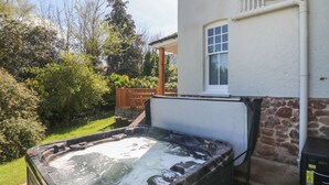 Un bain à remous dans un jardin, avec un mur en pierre et une fenêtre.