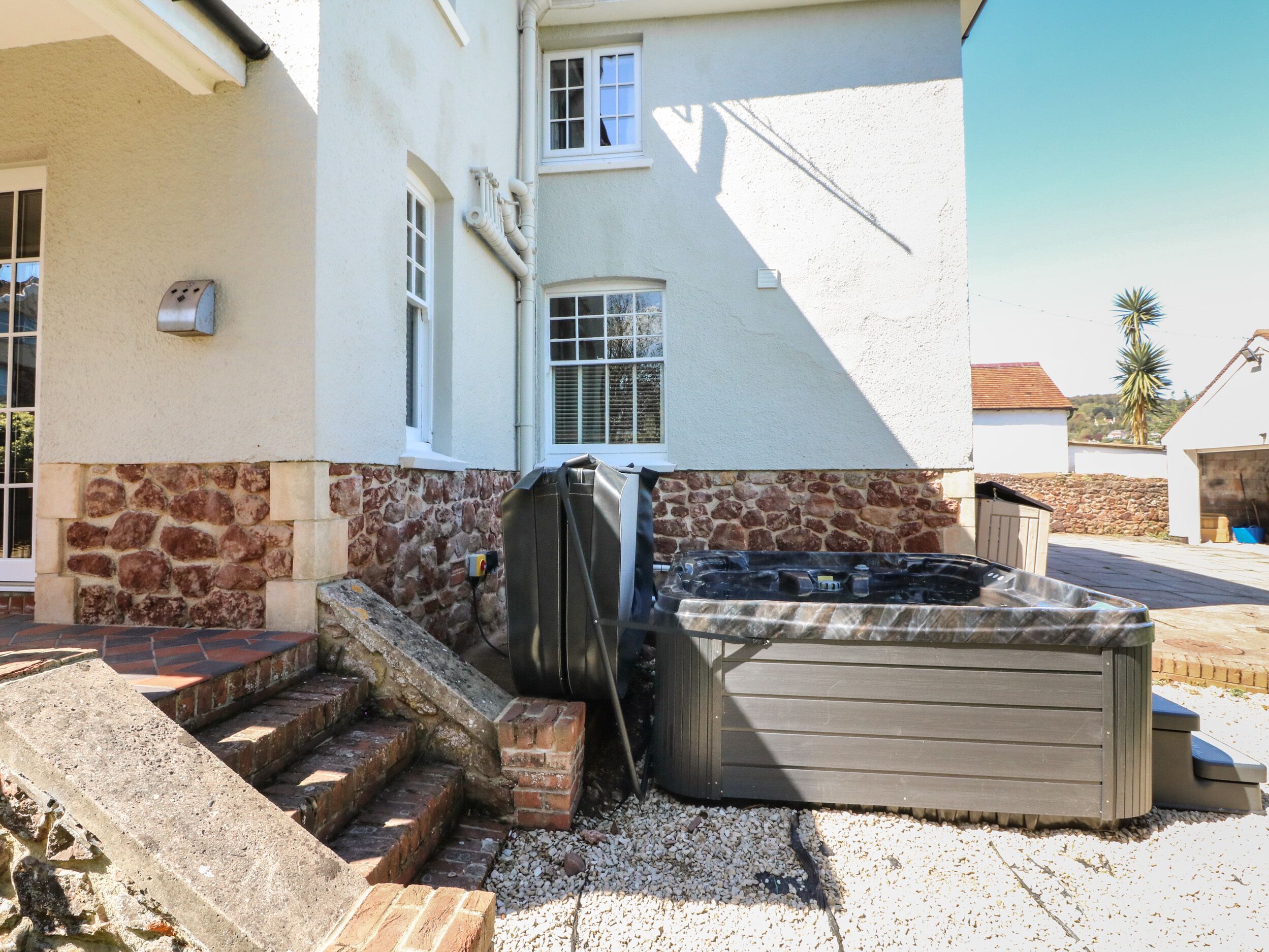 A house with a stone foundation, a wooden deck, and a hot tub.