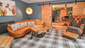 A modern living room with a sectional sofa, a tufted armchair, a plaid rug, and a coffee table. - Well Cottage (Beverley)