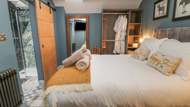 A bedroom with a bed, a walk-in closet, and a shower area. - Well Cottage (Beverley)