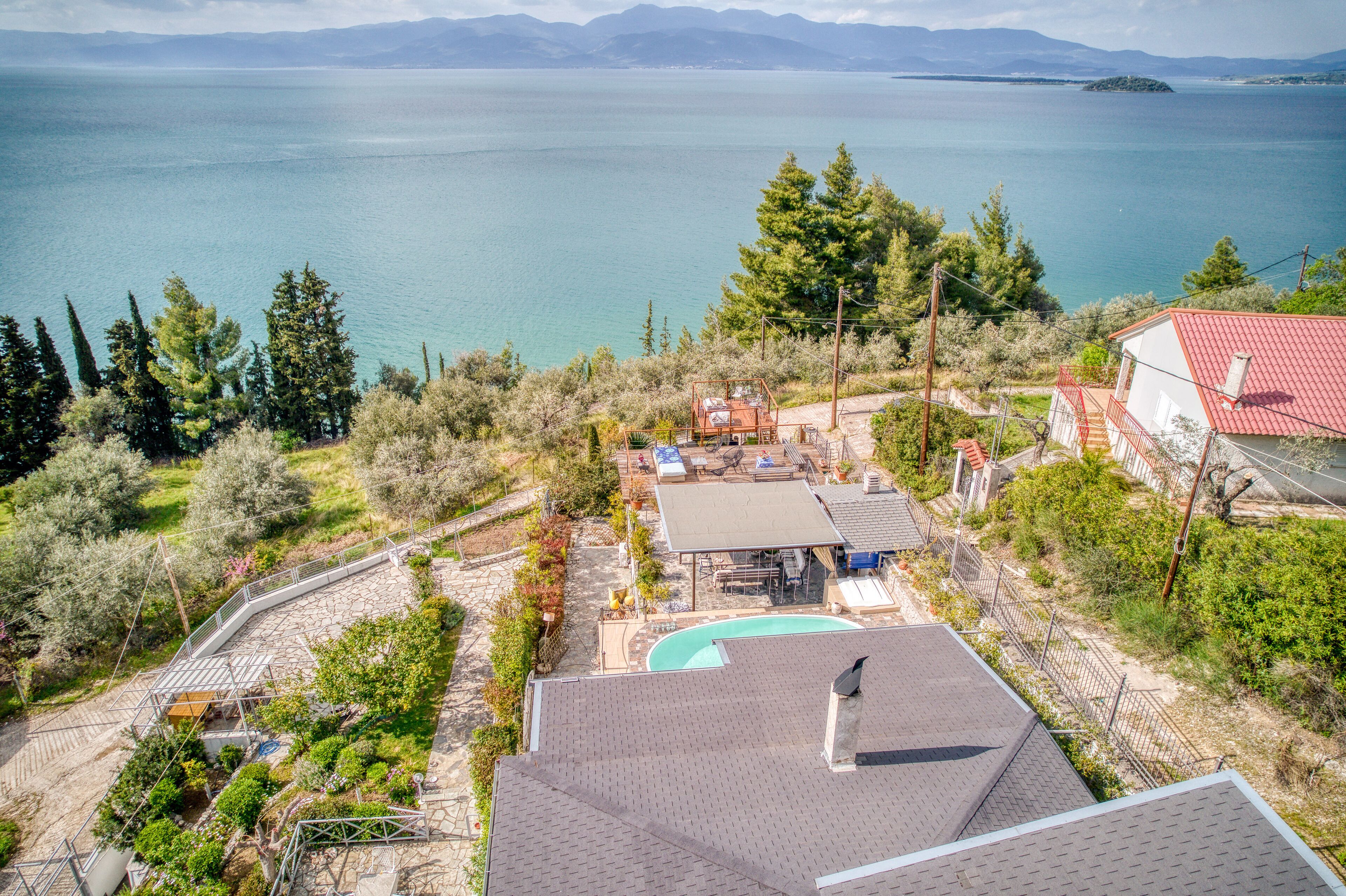A residential property with a swimming pool, outdoor seating area, and a view of a large body of water.