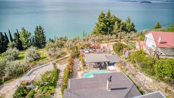 A residential property with a swimming pool, outdoor seating area, and a view of a large body of water.