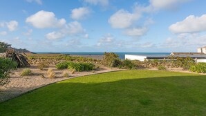 Une propriété située sur la côte, dotée d’une pelouse verdoyante, de murs en pierre et offrant une vue sur la mer.
