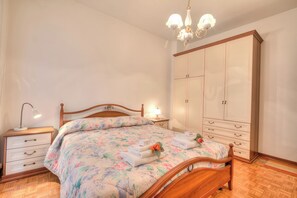 Un dormitorio con una cama de madera, una mesita de noche con lámpara, un armario y una araña.