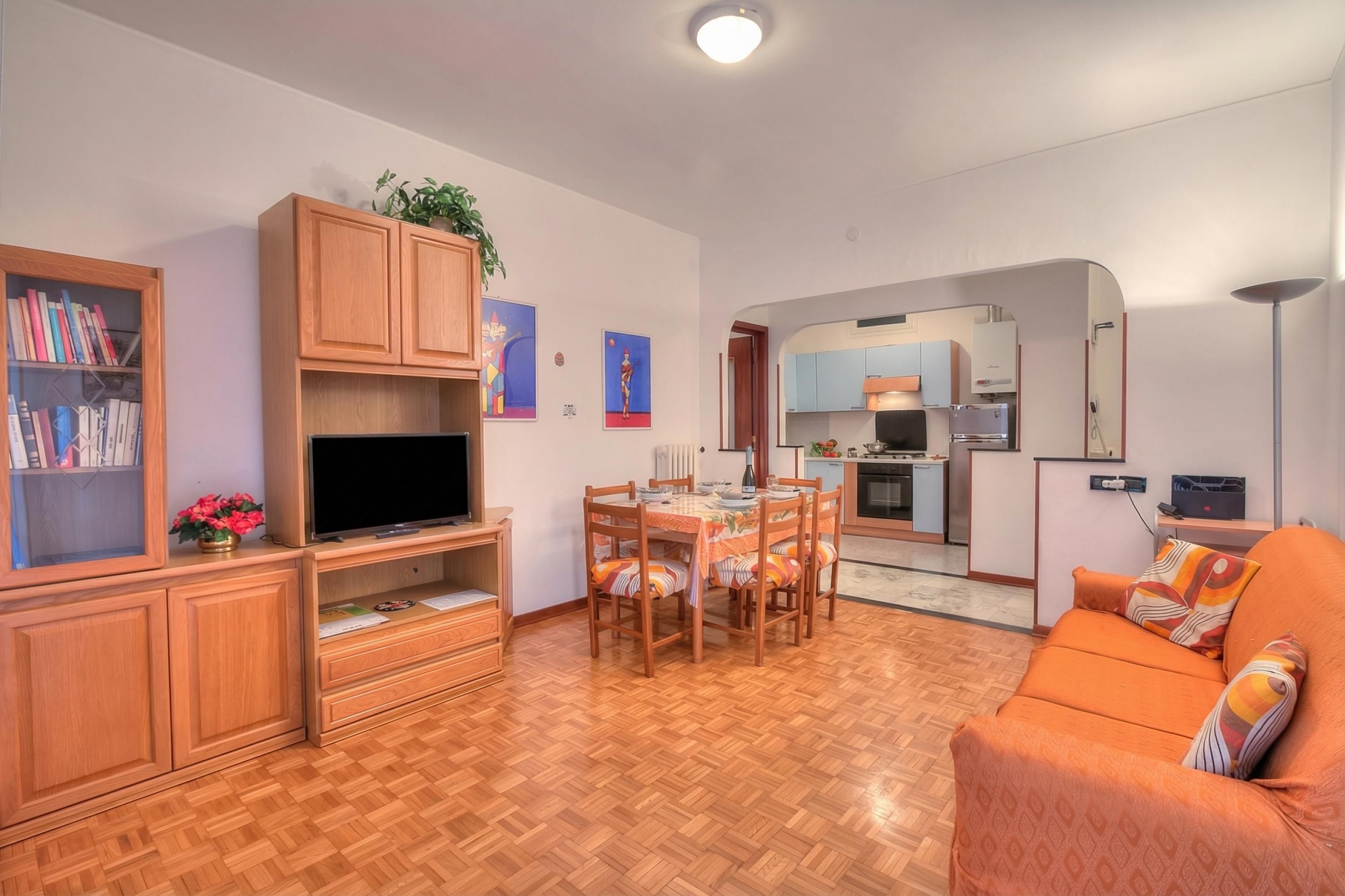 A living room with a TV, wooden cabinets, a dining table, and a sofa.