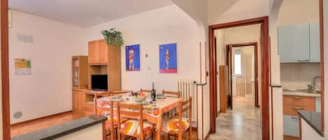 A dining area with a wooden table and chairs, a television, and artwork on the walls.