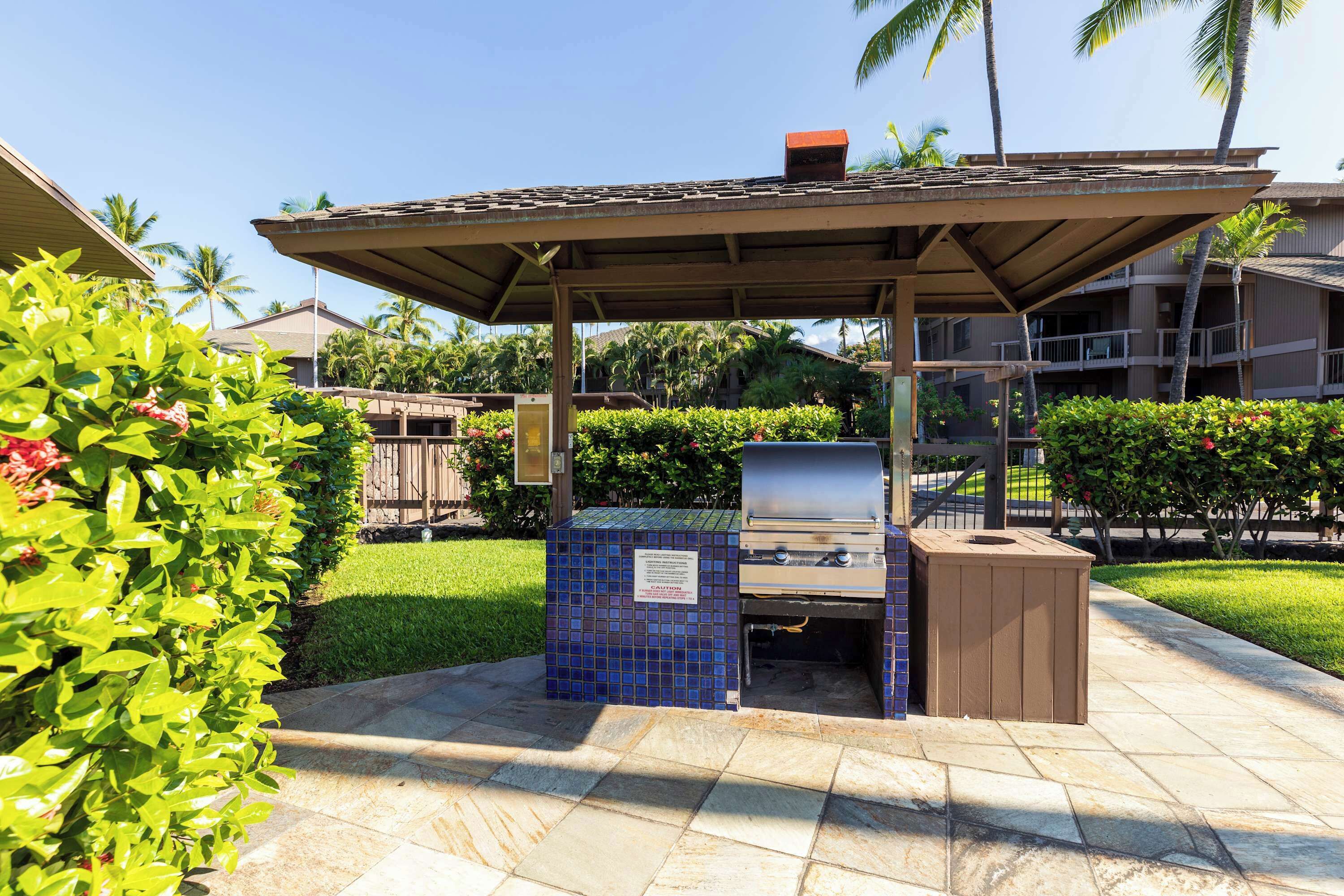 Ein Außenbereich mit Grillplatz, ummauert mit Fliesen, inklusive Grill und Mülleimer.