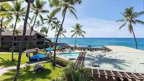 A resort with a pool, lounge chairs, and palm trees. - Konaloa Unimpeded Views of the Ocean (Kailua-Kona)