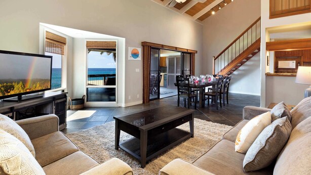A spacious living room with a large television, comfortable seating, and a view of the ocean through a glass door. - Konaloa Unimpeded Views of the Ocean (Kailua-Kona)