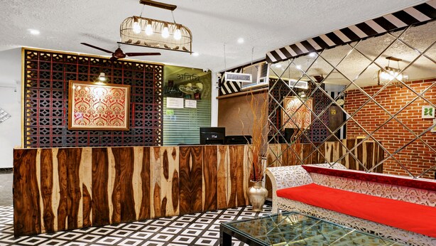 A reception area with a wooden reception desk, a sofa with a red cushion, and a patterned floor. - Itsy Hotels Banana Boutique (Varanasi)