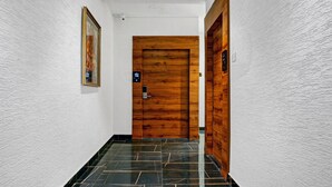 A hallway with a wooden door, a security camera, and a framed picture on the wall. - Itsy Hotels Banana Boutique (Varanasi)