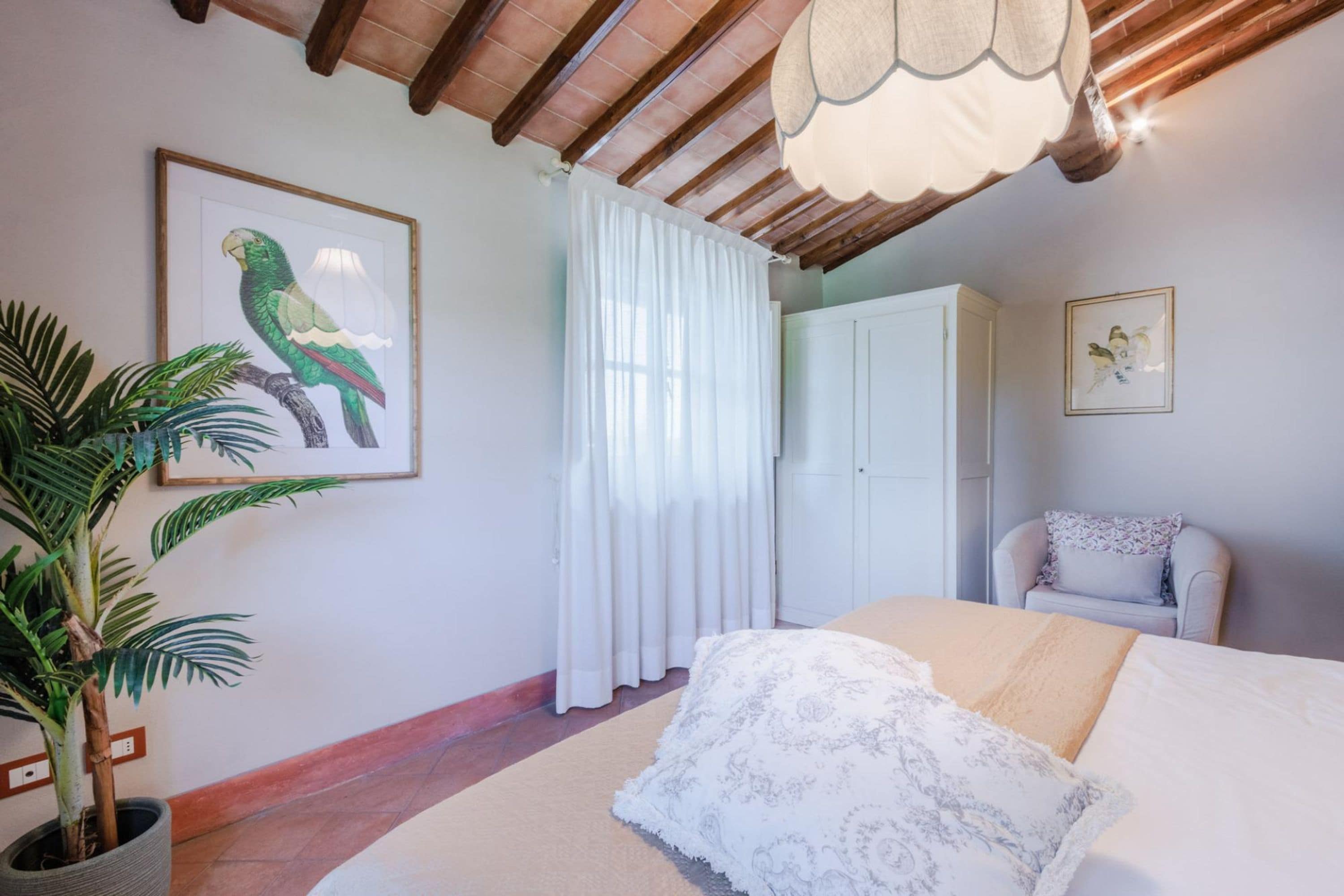 A bedroom with a bed, a potted plant, a wardrobe, and a chair.