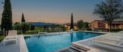 Una piscina con sillones de descanso y vistas a las montañas.