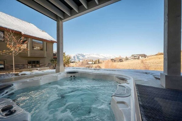 Relax in a hot tub under a covered structure with breathtaking mountain views.