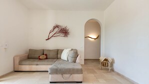 Un salon minimaliste avec un canapé, un pouf et une branche décorative.