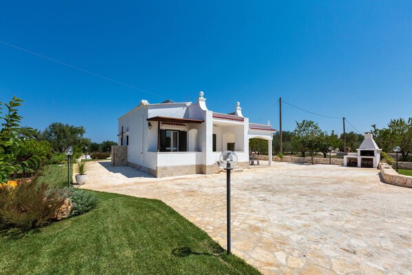 A modern house with a stone patio, a small garden, and a gazebo.