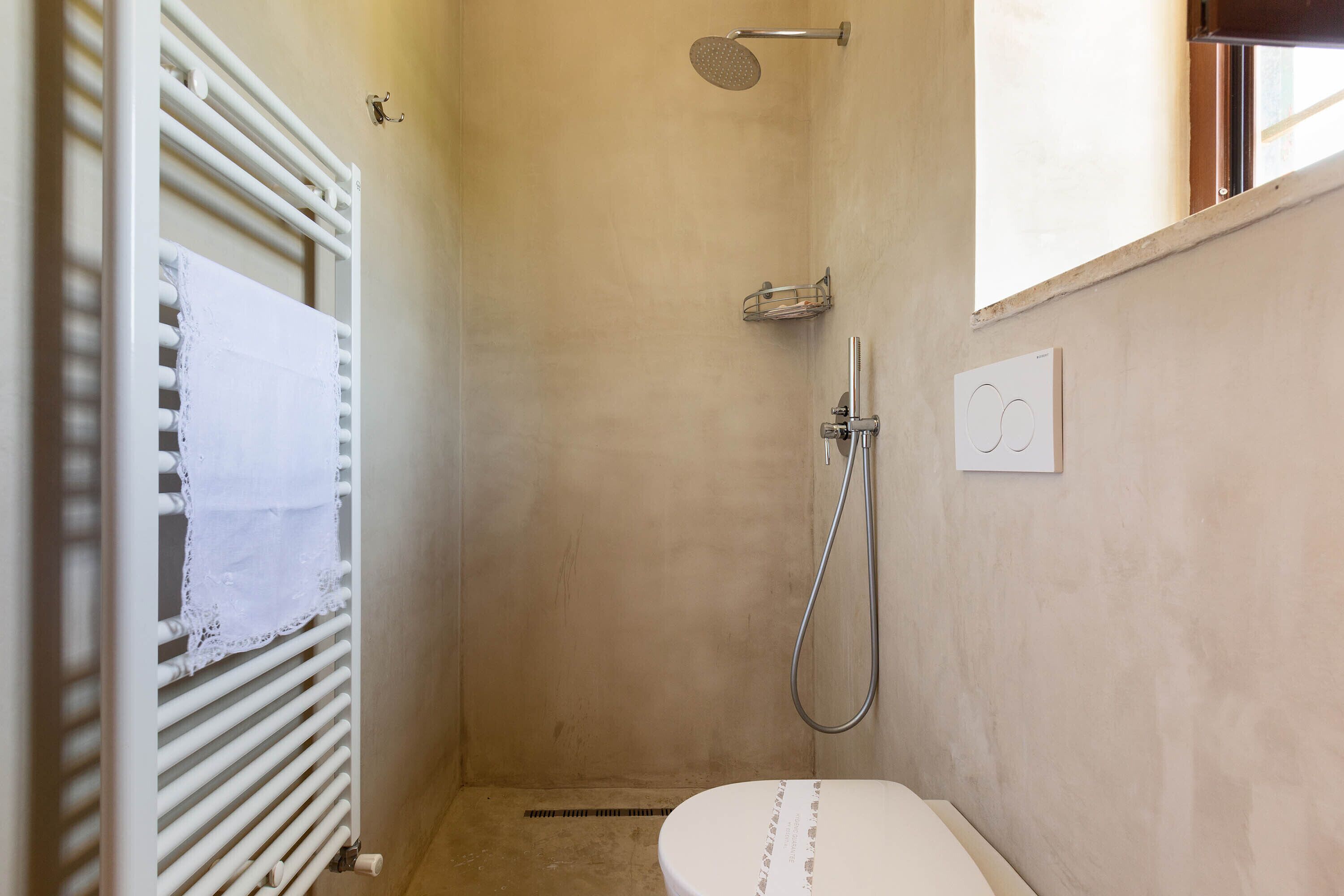 Un espacio de ducha pequeño y cerrado con inodoro, toallero y ducha.