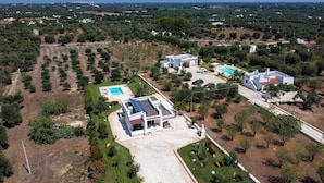 Vue aérienne d’un quartier résidentiel comprenant plusieurs maisons, une piscine et une pelouse bien entretenue.