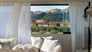 Una habitación con un ventanal grande con vistas a una colina con edificios.