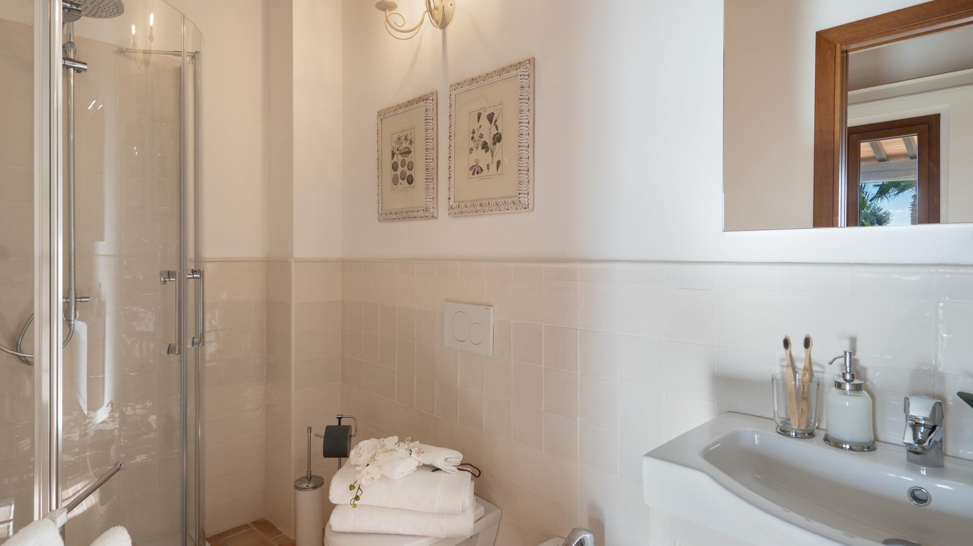 A bathroom with a glass shower enclosure, a toilet with a towel rack, and a sink with toiletries.
