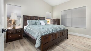 A bedroom with a large bed, nightstands, a dresser, and a window with blinds. - Cozy 2 bedroom house in Chandler (Chandler)