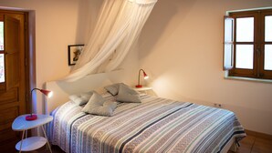 Ein Schlafzimmer mit Bett, Nachttisch, Lampe und Fenster.