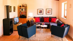 Ein gemütliches Wohnzimmer mit Kamin, Sofa, Sesseln und Bücherregal.
