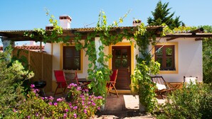 Ein Haus mit Garten, einer Holzpergola und einer Pflasterterrasse.