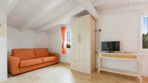 A room with a sofa, a wardrobe, a TV, and a window. - 2534 Appartamento Orange - Villa Sogno Blu by Barbarhouse (San Vito dei Normanni)