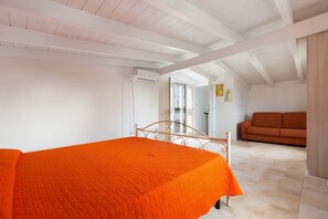 A bedroom with a bed, a sofa, and a door leading to another room. - 2534 Appartamento Orange - Villa Sogno Blu by Barbarhouse (San Vito dei Normanni)