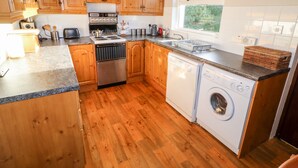 Una cocina con armarios de madera, estufa, lavabo y lavadora.
