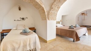 A room with two beds, a bench, and a stone archway. - 2770 Uliveto Valeria - Trullo Melograno by Perle di Puglia (San Michele Salentino)