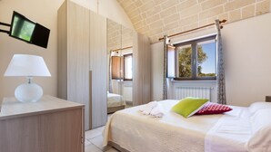 A bedroom with a bed, a desk, a lamp, a flat-screen TV, and a window with curtains. - 1963 Villa Ajeni by Perle di Puglia (San Michele Salentino)